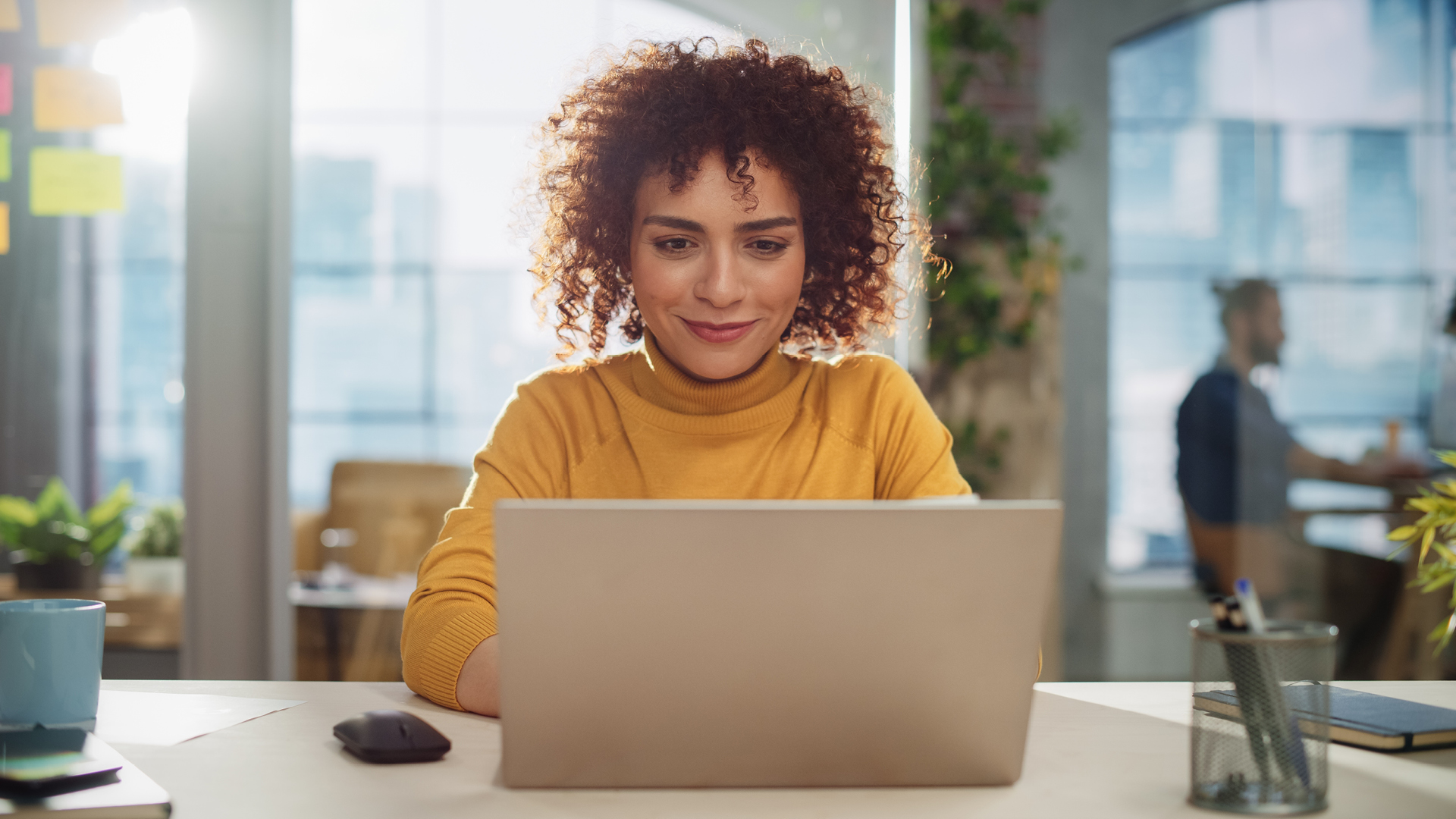 Women sitting at a laptop with sunlight coming through window behind her